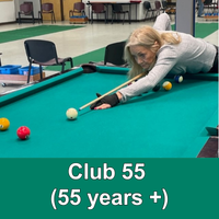 older lady playing 8 ball leaning over table with green banner with words Club 55 (55 years+)