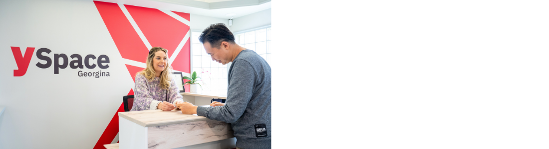 man standing at counter talking to woman with sign on the wall that states ySpace Georgina