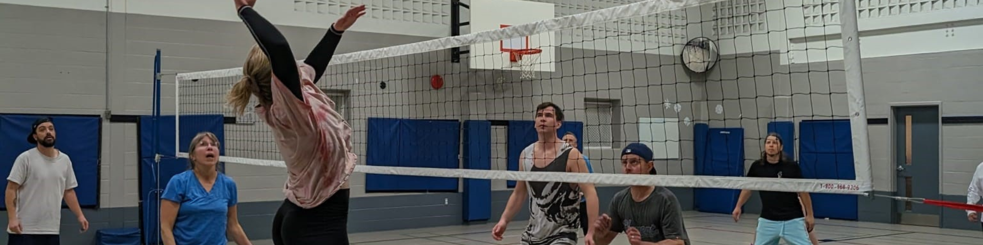 Adults playing indoor volleyball