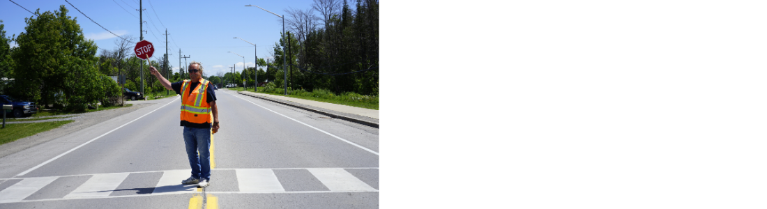 lone crossing guard standing in road holding up stop sign