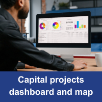 man sitting at a desk with computer on screen is a dashboard with blue bar and text Capital Projects map and dashboard