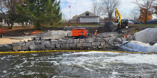 Stone wall at the waters edge with construction equipment