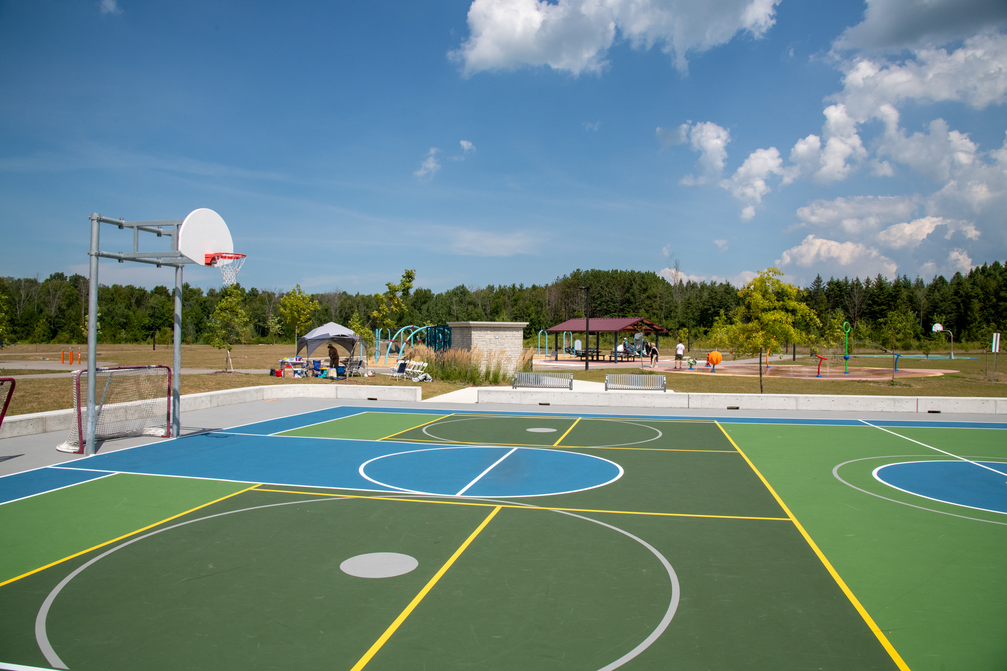 Brightly coloured basketball court with playground and pavillions in the background