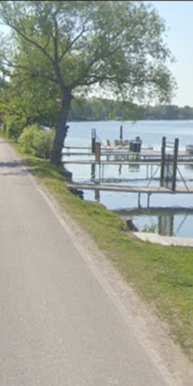 Road alongside a shoreline with docks along the road