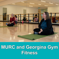 adults sitting on yoga mats with mirrors behind them