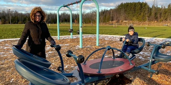 Mother and child sitting on accessible playground equipment