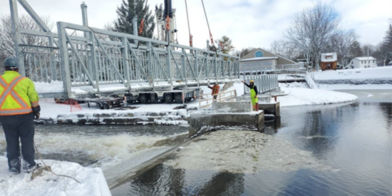 Construction workers aligning a metal bridge into place