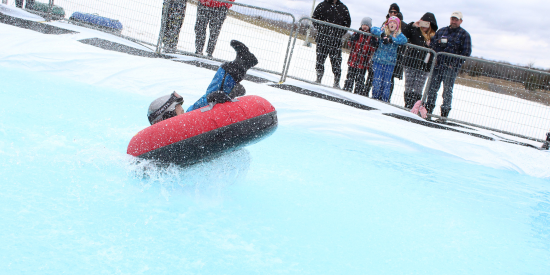 child on innertube in snow gear and helmet 