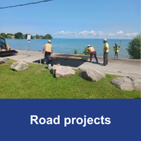 four construction workers working on a speed hump  with blue bar and text Road Construction