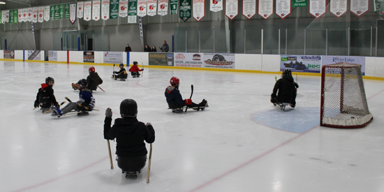 children playing sledge hockey on rink with sleds and protective equipment