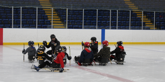 children playing sledge hockey on rink with sleds and protective equipment