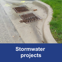 sewers in the road at the curb with blue bar and text stormwater projects