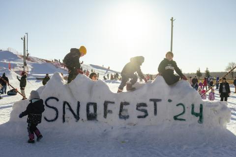 four children climbing on a snow castle with the words Snofest '24