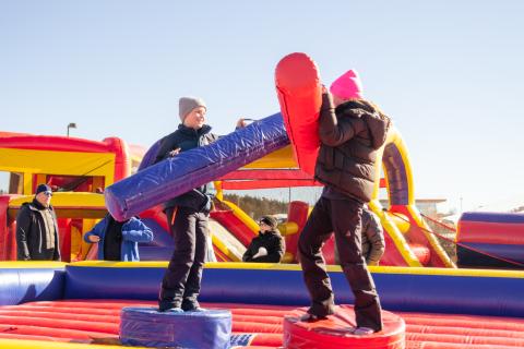 two teens on inflatable with large pads hitting each other