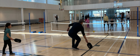 Family playing pickleball in a gymnasium