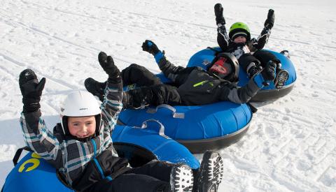 three children in tubes with arms in the air