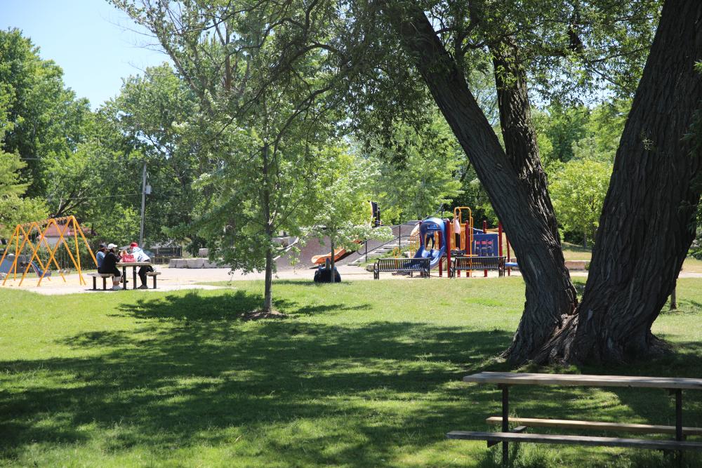 park with playground and people sitting at a picnic table