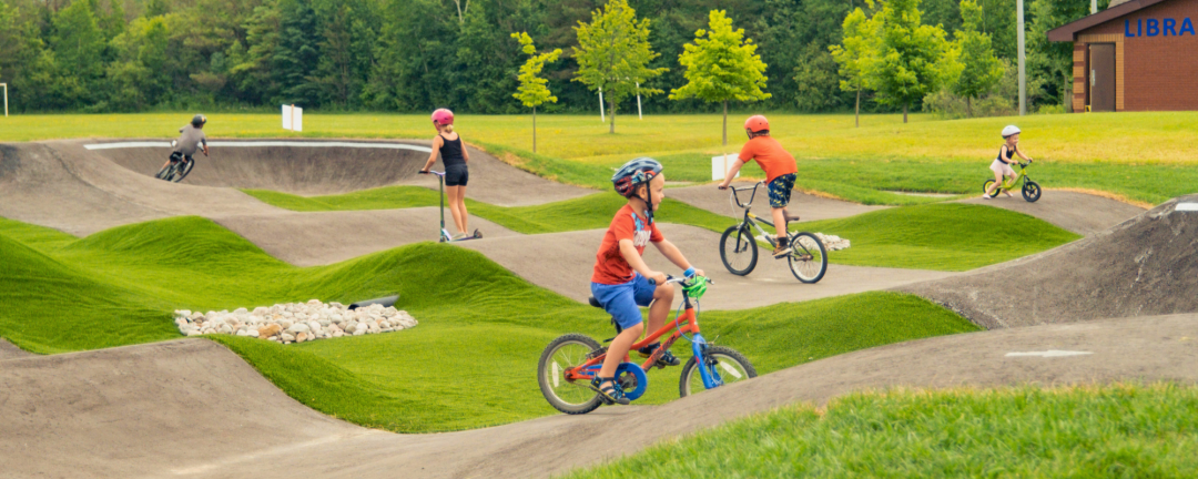 Kids riding bikes and skateboards at a skatepark