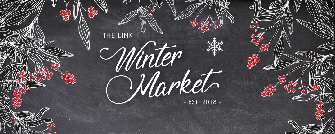 chalkboard background with red berries and the words, the link winter market established 2018