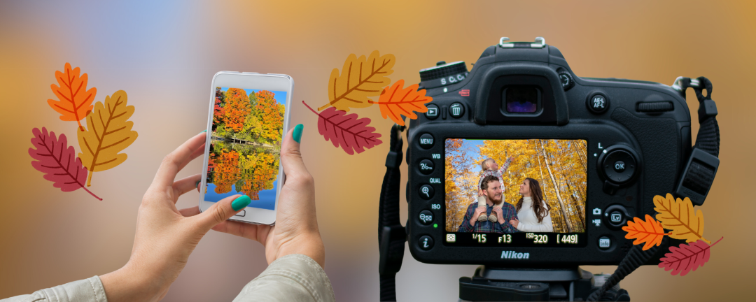 Hand holding a smartphone with an image of trees in the fall and a camera with an image of a family in the lens